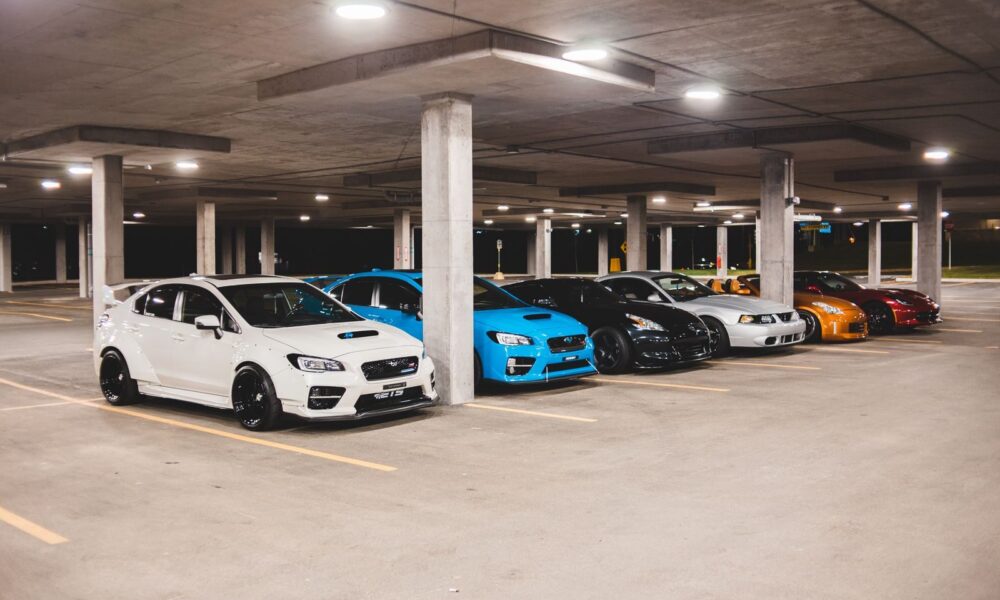 Bright new expensive automobiles placed on parking lot under concrete roof with bright lights