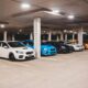 Bright new expensive automobiles placed on parking lot under concrete roof with bright lights
