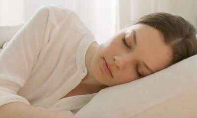 Calm woman sleeping in a white room, reflecting serenity and relaxation, ideal for lifestyle blogs.