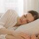 Calm woman sleeping in a white room, reflecting serenity and relaxation, ideal for lifestyle blogs.