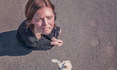 Aerial view of a frustrated woman on pavement next to spilled ice cream.
