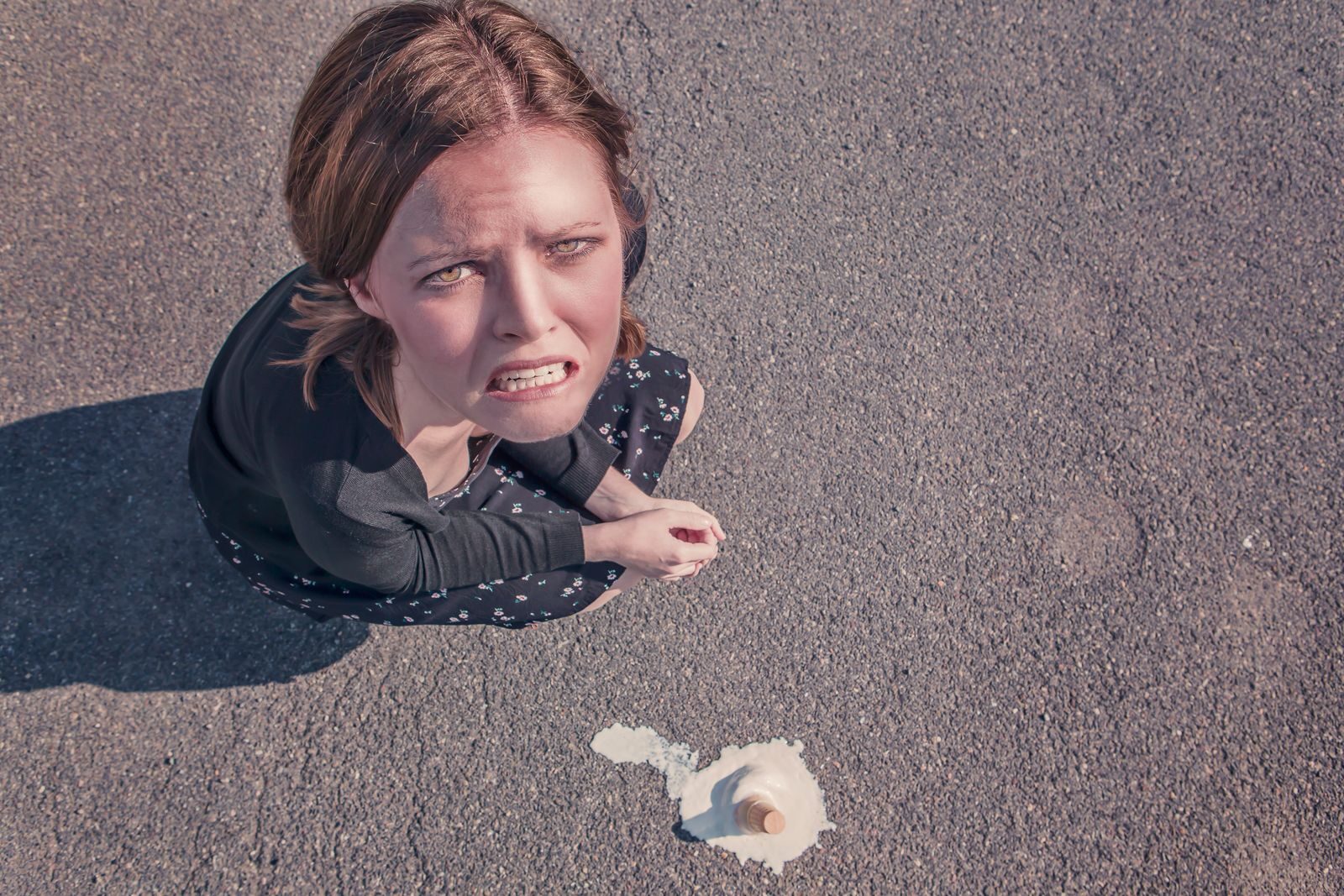 Aerial view of a frustrated woman on pavement next to spilled ice cream.
