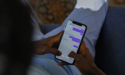 Close-up of hands holding a smartphone, typing a message on a touch screen indoors.