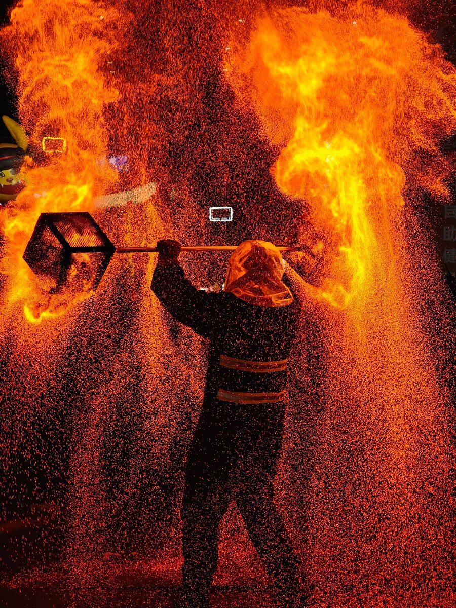 Stunning fire performer with flames and sparks in a nighttime show.