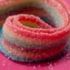 Vibrant close-up of colorful, sugary sour candy on a pink background.