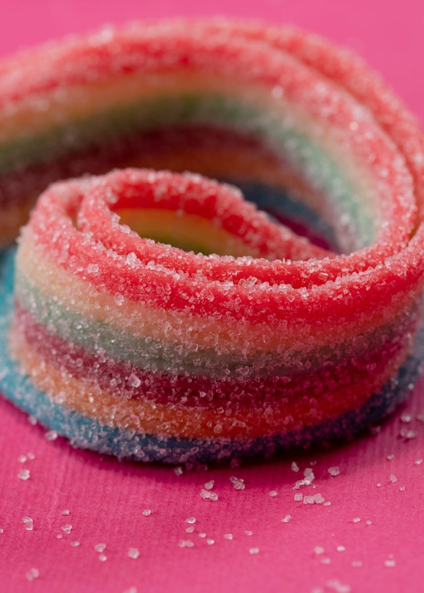 Vibrant close-up of colorful, sugary sour candy on a pink background.