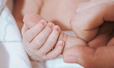 A newborn baby gently holds an adult's finger, symbolizing love and connection.