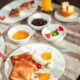 Close-up of a breakfast with sunny side eggs, toast, and juice on a marble table.