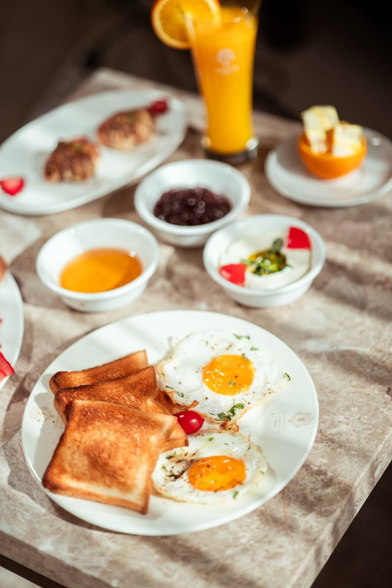 Close-up of a breakfast with sunny side eggs, toast, and juice on a marble table.