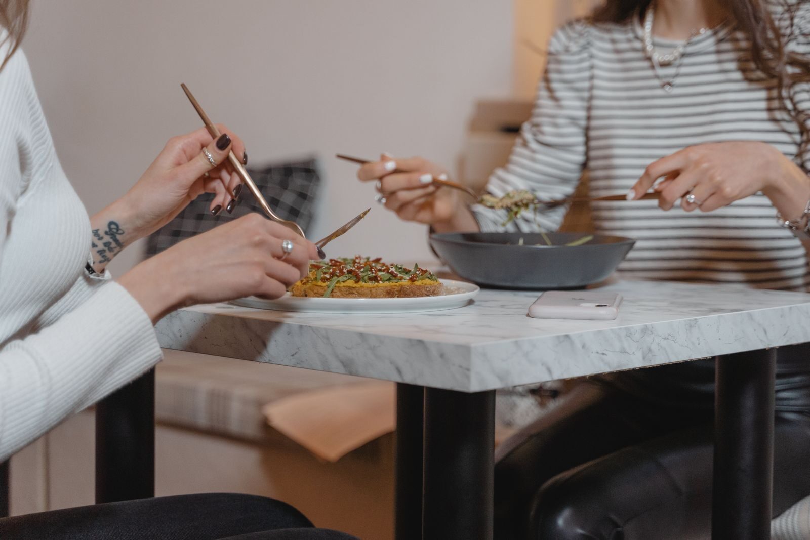 Two women sharing a healthy meal indoors, emphasizing friendship and togetherness.