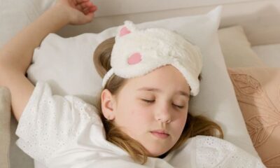 A young girl peacefully sleeping in bed with a soft eye mask, embodying comfort and innocence.