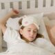 A young girl peacefully sleeping in bed with a soft eye mask, embodying comfort and innocence.
