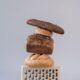 A creative stack of various breads against a grey backdrop for conceptual still life photography.