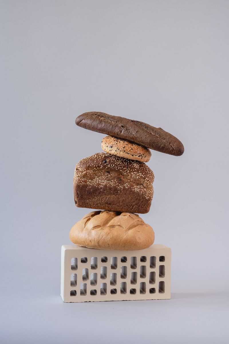 A creative stack of various breads against a grey backdrop for conceptual still life photography.