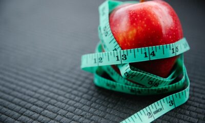 A vibrant red apple encircled by a blue measuring tape, symbolizing health and weight management.