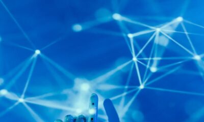 Futuristic robotic hand touching a digital network on a blue background.