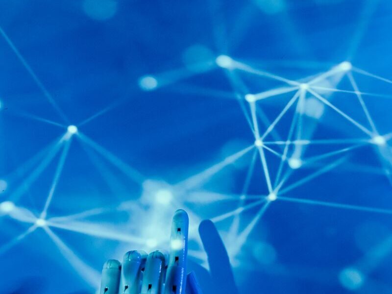 Futuristic robotic hand touching a digital network on a blue background.