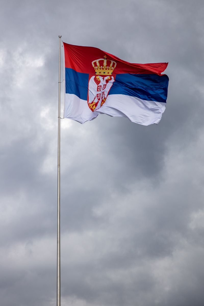 Serbian flag majestically waving against an overcast sky, showcasing national pride.