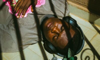A man lies serenely on a sunny balcony, listening to music through headphones.