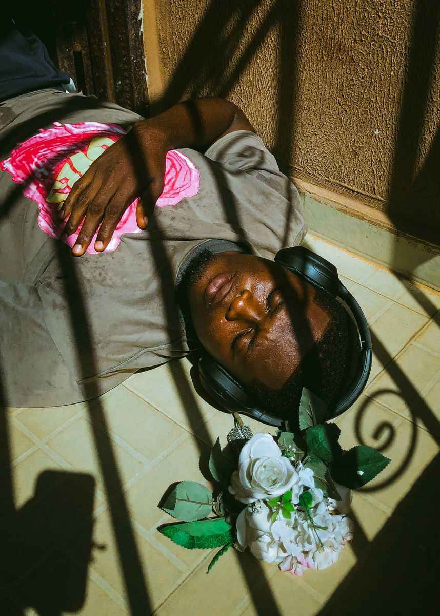 A man lies serenely on a sunny balcony, listening to music through headphones.