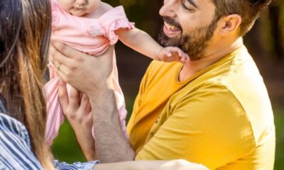 Father and mother enjoying sunny day with baby daughter outdoors.