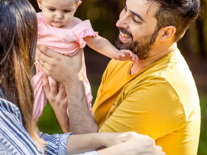 Father and mother enjoying sunny day with baby daughter outdoors.