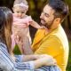 Father and mother enjoying sunny day with baby daughter outdoors.
