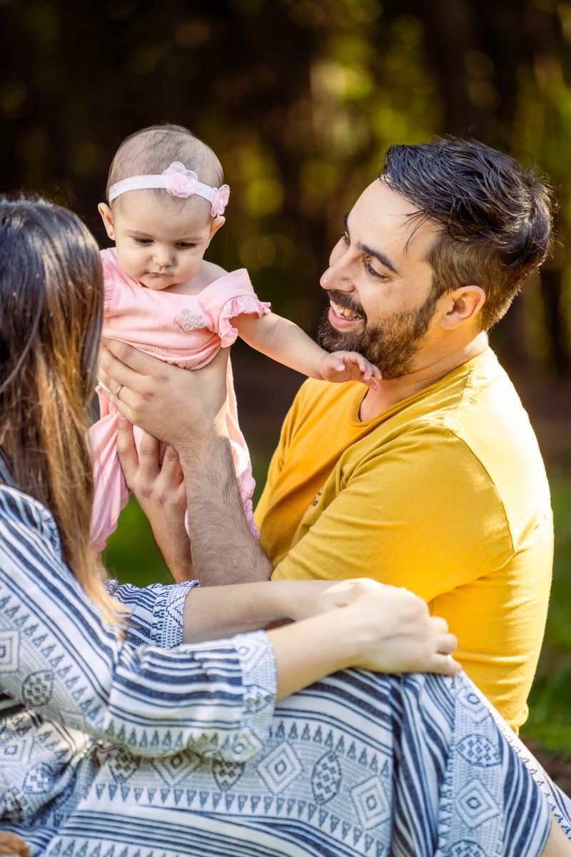 Father and mother enjoying sunny day with baby daughter outdoors.