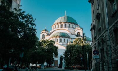 View of the iconic Saint Sava Temple in Belgrade on a sunny day, framed by trees and buildings.