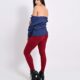 Stylish woman in blue sweater and red pants posing on a white background.