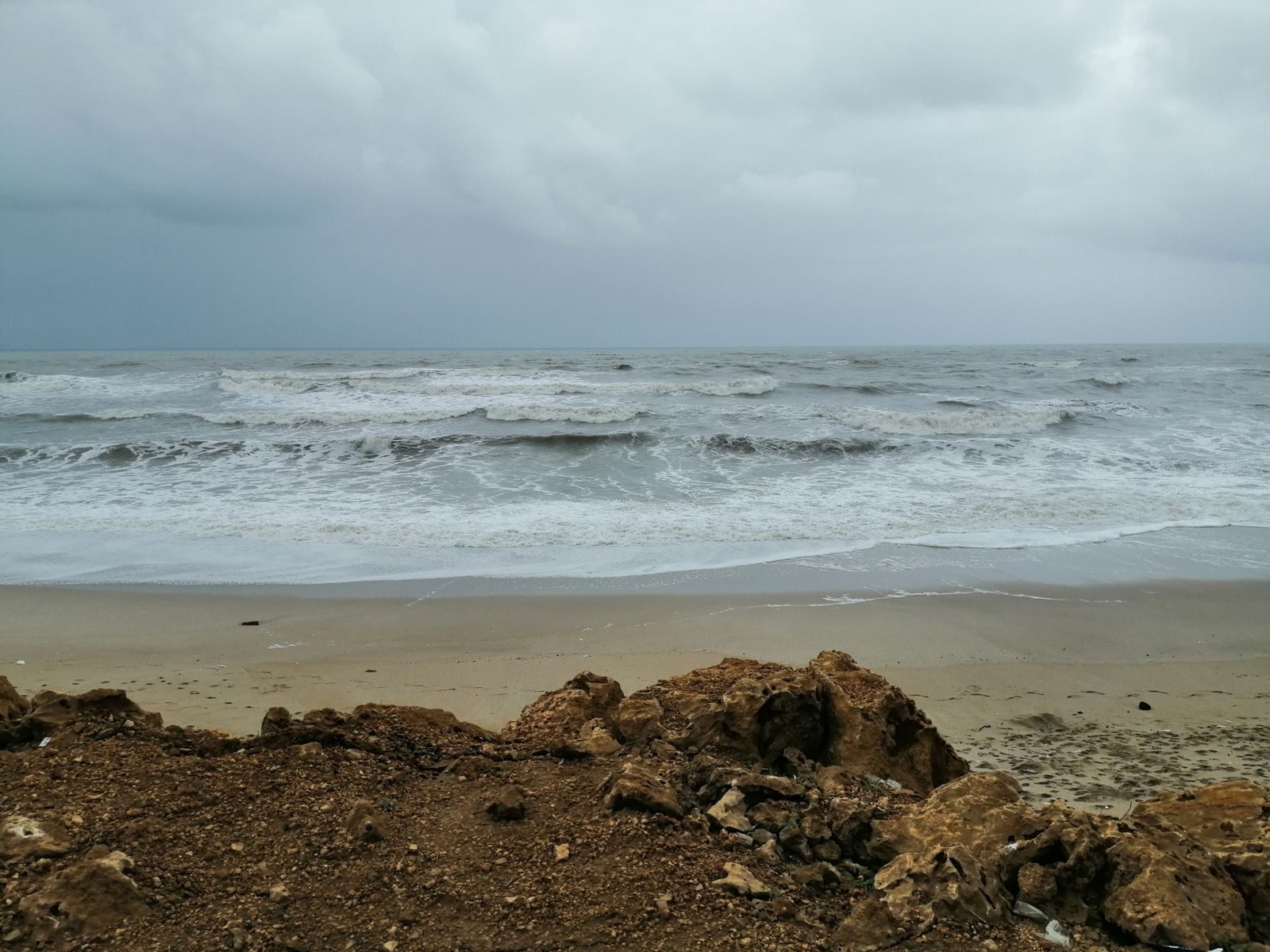 A dynamic view of the ocean with waves crashing against a rocky shore under a cloudy sky, ideal for dramatic landscapes.