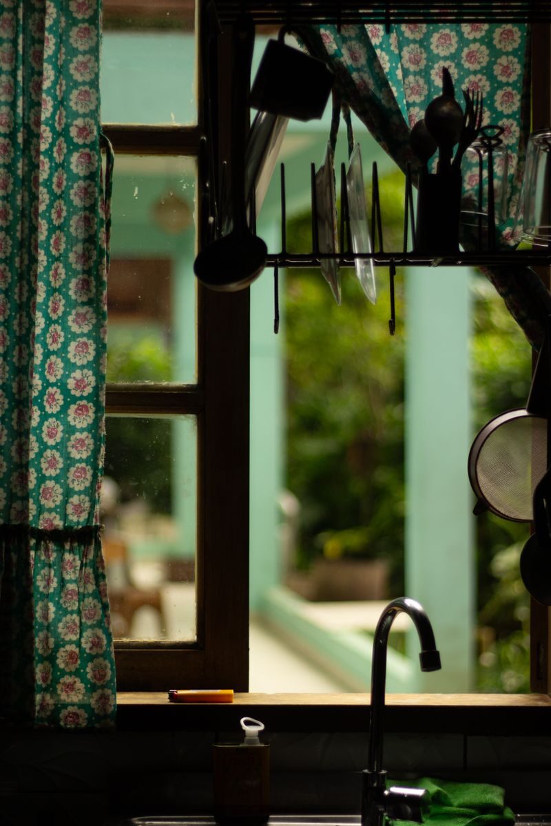 Charming kitchen sink area with utensils viewed through an open window.