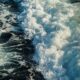 Aerial view of foamy ocean waves crashing in the deep blue sea, capturing the essence of nature's power and beauty.