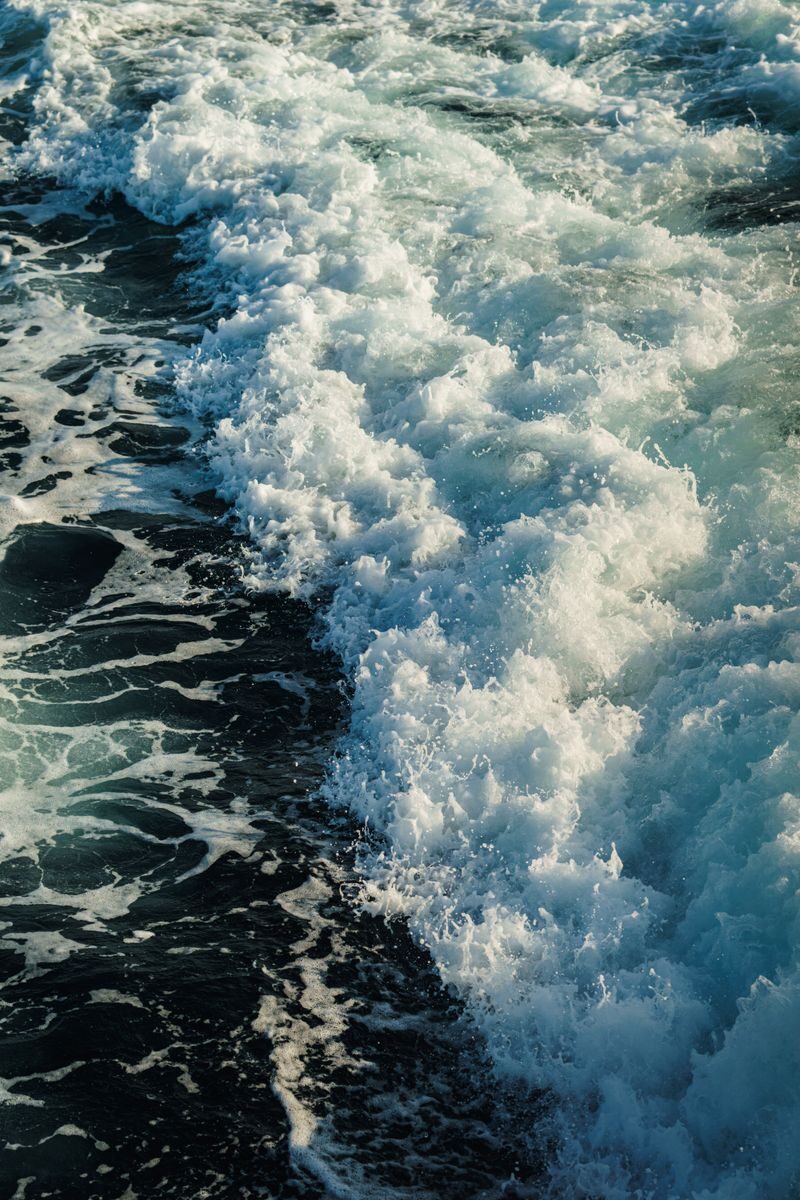 Aerial view of foamy ocean waves crashing in the deep blue sea, capturing the essence of nature's power and beauty.