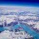 A stunning aerial view capturing a frozen landscape with snow-capped mountains and icy waters.
