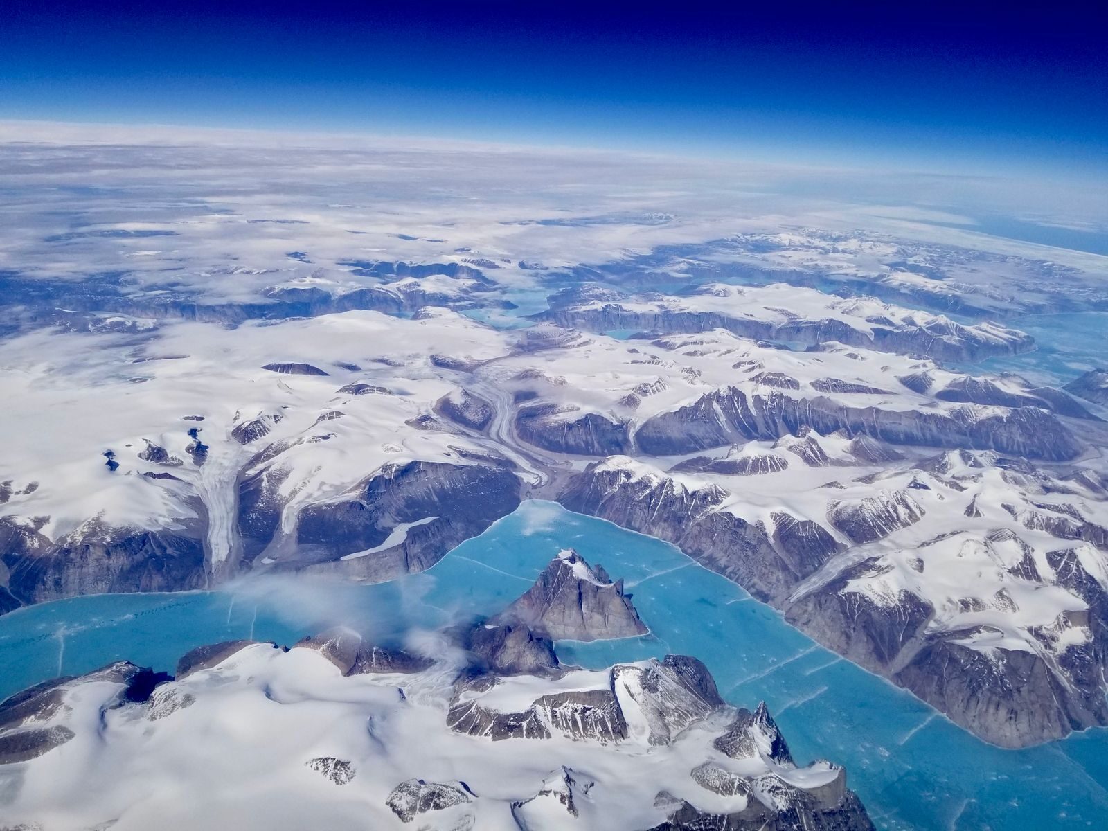 A stunning aerial view capturing a frozen landscape with snow-capped mountains and icy waters.