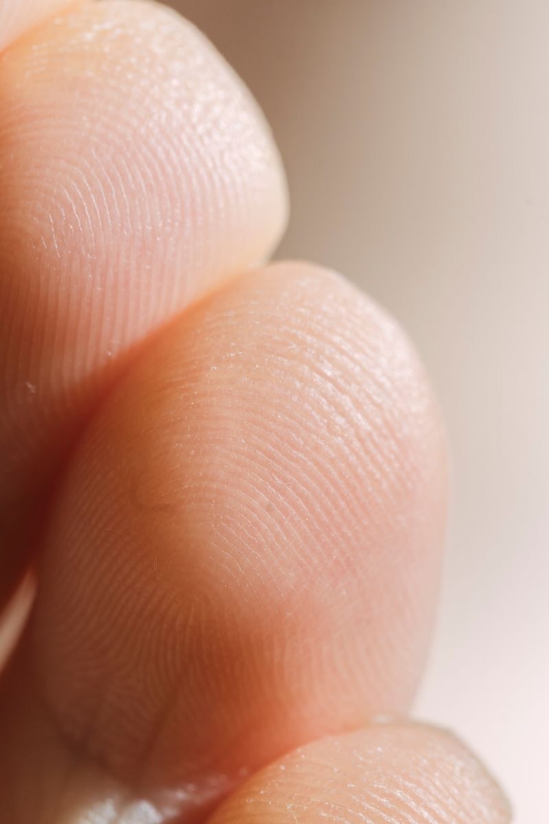 Closeup of finger pads with different ridge patterns and wrinkles of crop anonymous person standing in light room on white background