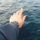 A hand reaching over the calm ocean, symbolizing freedom and exploration.