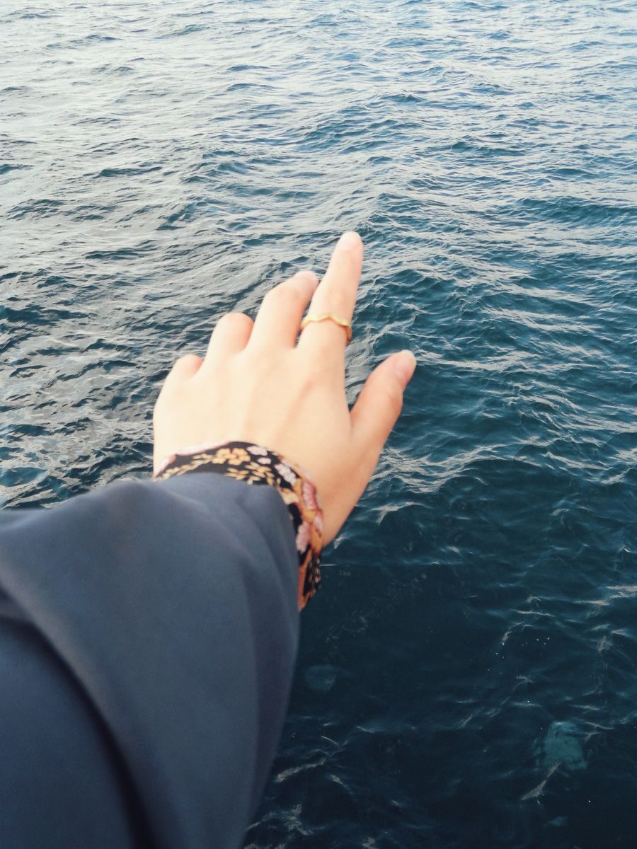 A hand reaching over the calm ocean, symbolizing freedom and exploration.