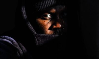 Moody portrait of a man in low light wearing a hooded jacket.