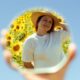 A woman enjoys a sunny day with sunflowers, reflected in a mirror.