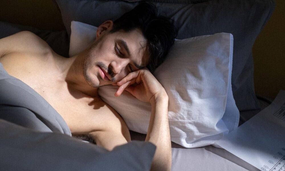 A man peacefully sleeping in a sunlit bedroom with natural light streaming in.