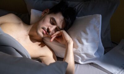 A man peacefully sleeping in a sunlit bedroom with natural light streaming in.