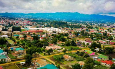 Drone shot of a vibrant townscape in Mbeya, Tanzania, surrounded by greenery and hills.