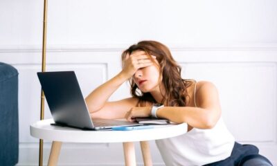 A woman showing signs of fatigue while working remotely at a laptop indoors.