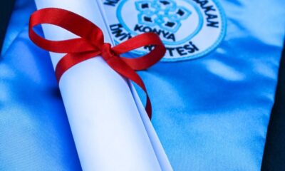 Rolled diploma with a red ribbon on a blue graduation gown, symbolizing academic achievement.