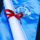 Rolled diploma with a red ribbon on a blue graduation gown, symbolizing academic achievement.
