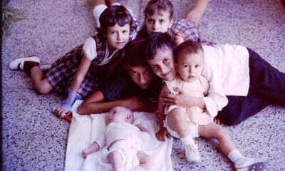 A heartwarming scene of siblings cuddled around a baby on a terrazzo floor.