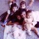 A heartwarming scene of siblings cuddled around a baby on a terrazzo floor.