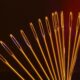 Artistic display of golden sewing needle eyes arranged in an arc against a dark backdrop.